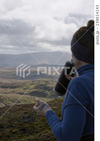 Woman hydrating during a highland mountain hike Woman hydrating during a highland mountain hike 139014143