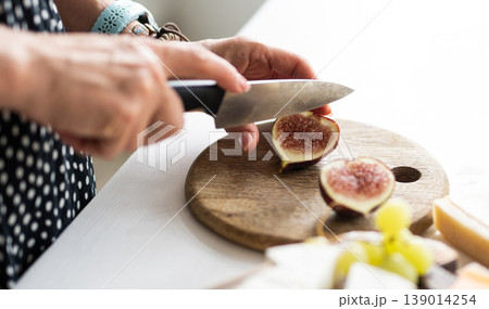 Woman Cutting Fresh Fig On A Cutting Board Woman Cutting Fresh Fig On A Cutting Board 139014254