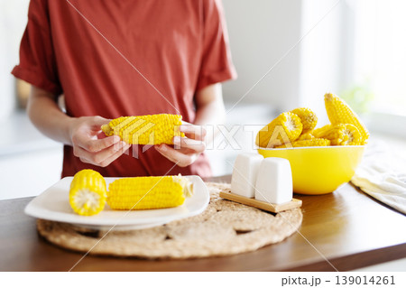 Young Girl Eating Boiling Corn Cobs For Eating 139014261
