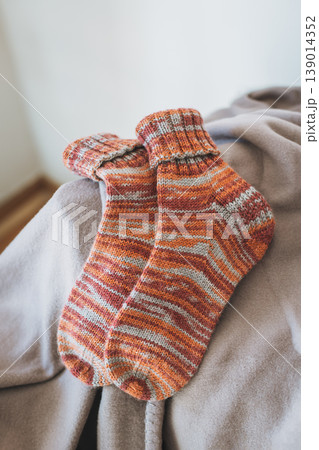 Hand knitted cosy socks on a blanket. Concept for handmade and hygge slow life. 139014352