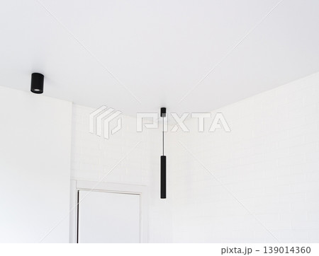 Minimalist interior showcasing modern black linear pendant and spot lights against a white brick wall and clean ceiling Minimalist interior showcasing modern black linear pendant and spot lights against a white brick wall and clean ceiling 139014360