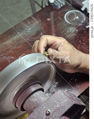 Artisan Hands Polishing a Gemstone on a Lapidary Grinding Wheel in Jewelry Workshop Artisan Hands Polishing a Gemstone on a Lapidary Grinding Wheel in Jewelry Workshop 139014826