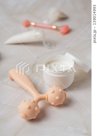 Skincare beauty routine with cosmetic tubes, cream jar and facial massage rollers on marble background, wellness concept Skincare beauty routine with cosmetic tubes, cream jar and facial massage rollers on marble background, wellness concept 139014993