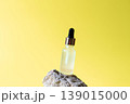 Cosmetic serum dropper bottle on natural stone with bright yellow background, skincare oil beauty product concept 139015000