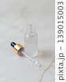 Glass cosmetic droppers with transparent serum on mirror surface, skincare essence drops and reflection, beauty treatment concept, minimalist cosmetic product background. 139015003