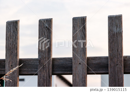 Weathered wooden fence boards against bright sky close up. Rustic outdoor background with copy space and minimal composition. Weathered wooden fence boards against bright sky close up. Rustic outdoor background with copy space and minimal composition. 139015115