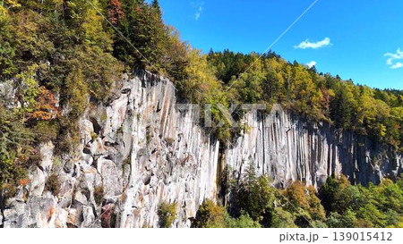 【空撮】連続する巨大な柱状節理！層雲峡のダイナミックな岩壁と紅葉の渓谷 139015412
