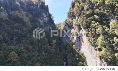 【空撮】秋色に染まり始めた層雲峡の断崖絶壁と奥にそびえる山々（北海道） 139015430