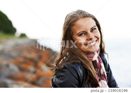 Portrait, happy woman and smile on face for outside, trip or travel on holiday to coastline. Young person, excited emoji or expression with trendy, style and fashion on vacation, nature and Ireland Portrait, happy woman and smile on face for outside, trip or travel on holiday to coastline. Young person, excited emoji or expression with trendy, style and fashion on vacation, nature and Ireland 139016196