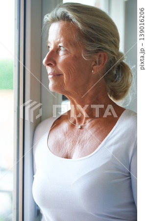 Senior, woman and thinking of nostalgia in home with smile for fond memory, peace or happiness. Elderly person, looking and window with relaxed expression on face for wellness, care and retirement 139016206