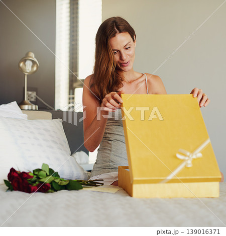 Woman, bedroom and open box with roses, present and happy for surprise on birthday, valentines day and event. Girl, cardboard package and gift with smile on bed with thinking in home for celebration 139016371