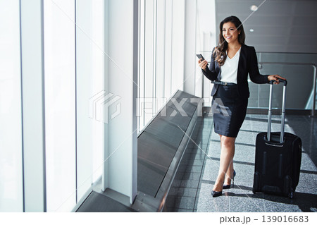 Business woman, phone and bag by airport window with smile, thinking and vision for international travel. Entrepreneur, suitcase and smartphone with flight schedule for global immigration in London 139016683
