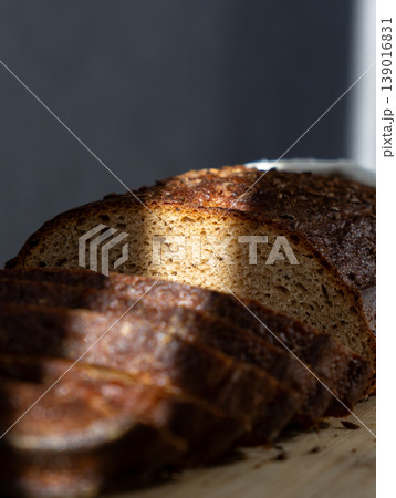 sliced brown bread lies on wooden board. ray of light. Sourdough rye bread with crispy crust. sliced brown bread lies on wooden board. ray of light. Sourdough rye bread with crispy crust. 139016831