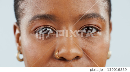 Eyes, looking and portrait of black woman in studio for vision, eyesight and focus on blue background. Healthcare, optometry and isolated face closeup of person with cosmetics, wellness and eye care Eyes, looking and portrait of black woman in studio for vision, eyesight and focus on blue background. Healthcare, optometry and isolated face closeup of person with cosmetics, wellness and eye care 139016889