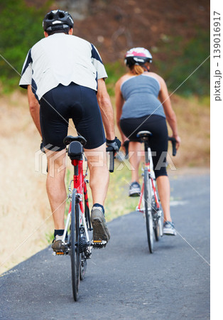 Back, road and couple cycling in nature for cardio, fitness and training on bicycle together. Outdoor, people and exercise on bike for fun, workout and travel in countryside adventure or journey Back, road and couple cycling in nature for cardio, fitness and training on bicycle together. Outdoor, people and exercise on bike for fun, workout and travel in countryside adventure or journey 139016917