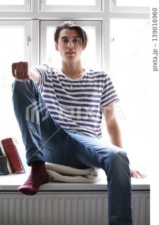 Portrait, window and an asian man in the bedroom of his home to relax in the morning of a weekend in summer. Fashion, style and a confident young model chilling in his apartment for time off 139016960