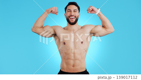 Happy man, portrait and muscle flex of bodybuilder in fitness isolated against a blue studio background. Male person, athlete or model smile showing strength, power or results for workout on mockup Happy man, portrait and muscle flex of bodybuilder in fitness isolated against a blue studio background. Male person, athlete or model smile showing strength, power or results for workout on mockup 139017112