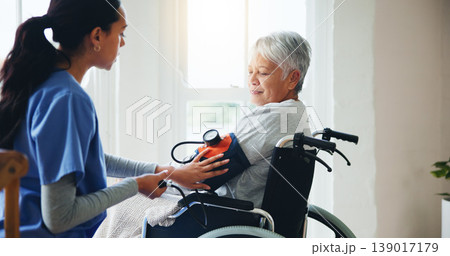 Woman, nurse and senior in wheelchair for blood pressure, monitoring or elderly care at old age home. Doctor or medical caregiver checking BPM of mature patient or person with a disability at house Woman, nurse and senior in wheelchair for blood pressure, monitoring or elderly care at old age home. Doctor or medical caregiver checking BPM of mature patient or person with a disability at house 139017179