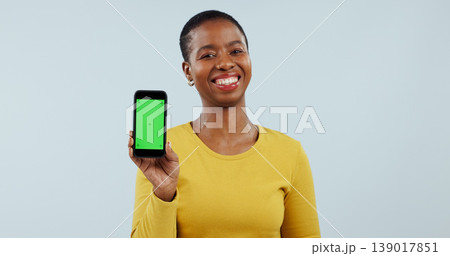 Happy black woman, portrait and phone green screen for advertising against a gray studio background. Face of African female person smile showing mobile smartphone display, marketing or app on mockup 139017851