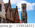 Sunny view of the Belfry of Bruges rising above the historic Markt square, showcasing medieval Flemish architecture under a clear blue sky, Brugge, West Flanders, Belgium 139018251