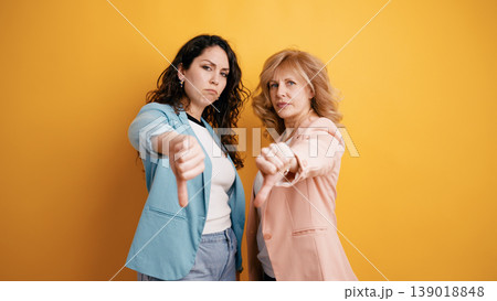 Two women showing disagreement with thumbs down gesture Two women showing disagreement with thumbs down gesture 139018848