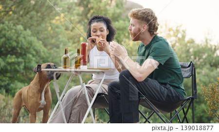 Couple eating hot dogs with dog at outdoor picnic 139018877
