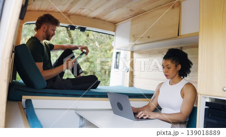 Couple working and relaxing inside a camper van Couple working and relaxing inside a camper van 139018889