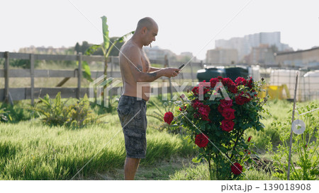 Man taking picture of red roses in urban garden 139018908