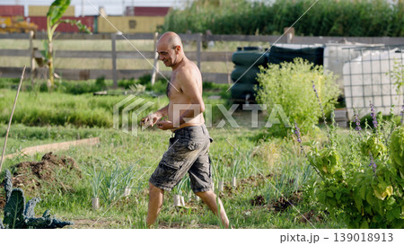 Man working in urban community garden harvesting vegetables 139018913