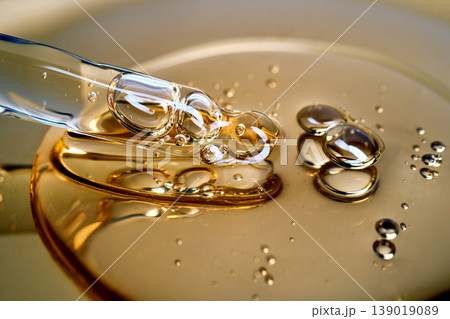 Pipette drawing golden liquid serum with bubbles 139019089