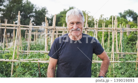 Happy confident senior man standing at community garden Happy confident senior man standing at community garden 139019893