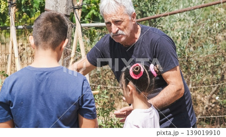 Elderly man explaining planting techniques to grandchildren at garden Elderly man explaining planting techniques to grandchildren at garden 139019910