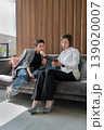 Businesswomen holding notepad brainstorming and discussing together sitting on sofa at office. Brainstorm, notepad, business, teamwork, office. 139020007