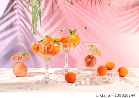 Alcoholic cocktail or punch, peach, apricot and mint berries on elegant background, minimalist concept for bar and holiday party, cafe, advertising banner, Modern still life with fruits. Alcoholic cocktail or punch, peach, apricot and mint berries on elegant background, minimalist concept for bar and holiday party, cafe, advertising banner, Modern still life with fruits. 139020244