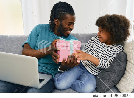 African American father gives his daughter a birthday present he ordered on the internet from his laptop. Positive daddy communicates with his child, happy family African American father gives his daughter a birthday present he ordered on the internet from his laptop. Positive daddy communicates with his child, happy family 139020825