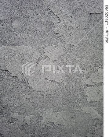 Close view of a grey decorative plaster wall highlights textured surface. The wall has a rugged look typical of industrial spaces. Light hits the surface, enhancing its features. Close view of a grey decorative plaster wall highlights textured surface. The wall has a rugged look typical of industrial spaces. Light hits the surface, enhancing its features. 139020968
