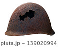 An antique soldier helmet from World War II shows a shell hole. It is isolated against a plain background, highlighting its aged metal and history. 139020994