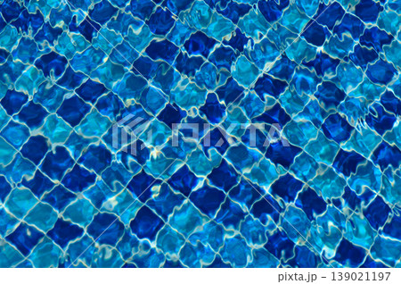 Rippling reflections dance on the shimmering surface of clear blue swimming pool 139021197