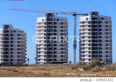 New residential buildings under construction with cranes in a sunny location near the coastline 139021321