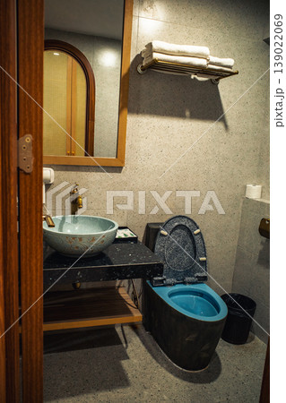 ホテルのバスルーム。石造りの洗面ボウルと模様入りのトイレがあるインテリア 139022069