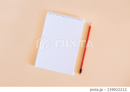 Notebook with blank page and pencil on light orange background. Notebook with blank page and pencil on light orange background. 139022212