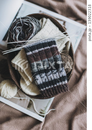 Hand knitted socks with needles and yarn ball in a basket. Concept for handmade and hygge slow life. Hand knitted socks with needles and yarn ball in a basket. Concept for handmade and hygge slow life. 139022318