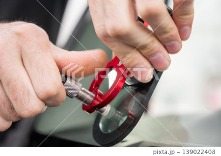 A technician injects resin into a windshield crack. A technician injects resin into a windshield crack. 139022408