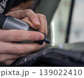 A technician drills a hole during a car windshield chip repair. 139022410