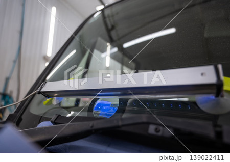 Windshield chip repair. A UV lamp dries the resin in the crack. 139022411