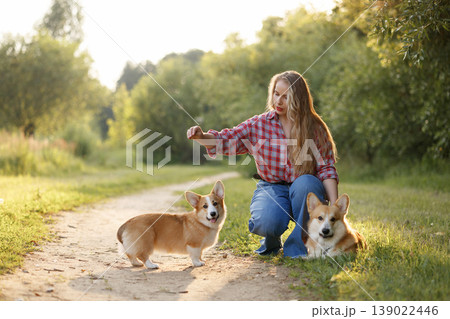 Young Woman And Corgi Playing. Caucasian Woman Kneels Down Outdoors With Her Corgi Puppy 139022446