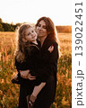 Mother Embraces Daughter. Gentle Silhouette Of Mother Shielding Daughter In Field Glow 139022451