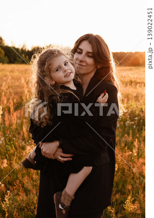 Mother Embraces Daughter. Gentle Silhouette Of Mother Shielding Daughter In Field Glow Mother Embraces Daughter. Gentle Silhouette Of Mother Shielding Daughter In Field Glow 139022451