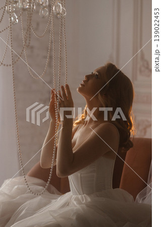 Refined Woman Dressed Stylishly Looks At Glowing Ceiling Lamp Amidst Soft Shadows 139022453