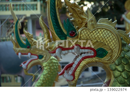 Golden Naga serpent statue detail at public Thai temple, mythological guardian sculpture and traditional Buddhist architecture. Golden Naga serpent statue detail at public Thai temple, mythological guardian sculpture and traditional Buddhist architecture. 139022974